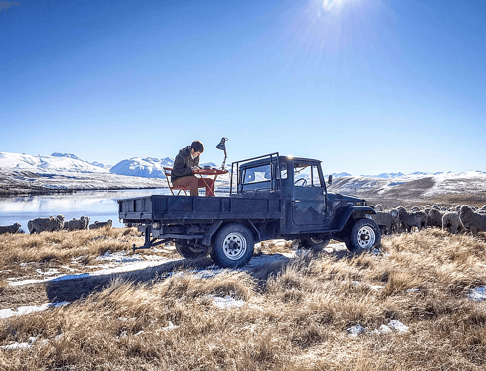 A Man working on office matter on a van. The van is parked in a beautiful place and away from civilization